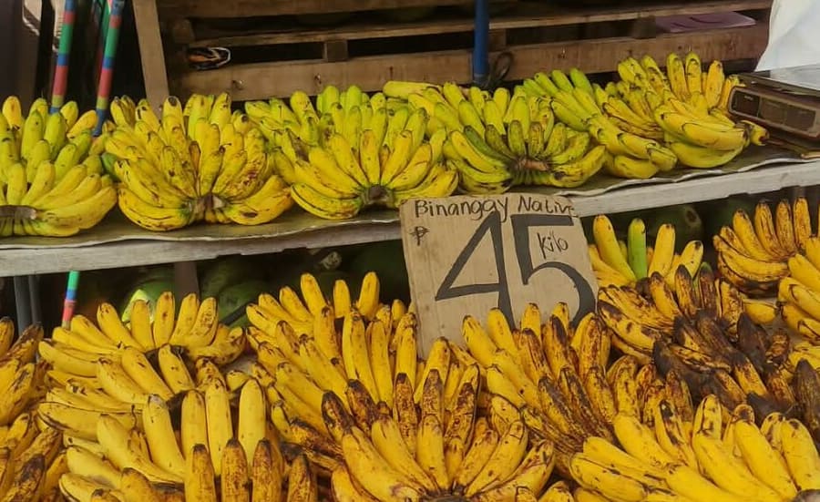 Bananas piled on a market stall with a handwritten price sign reading 45 a kilo